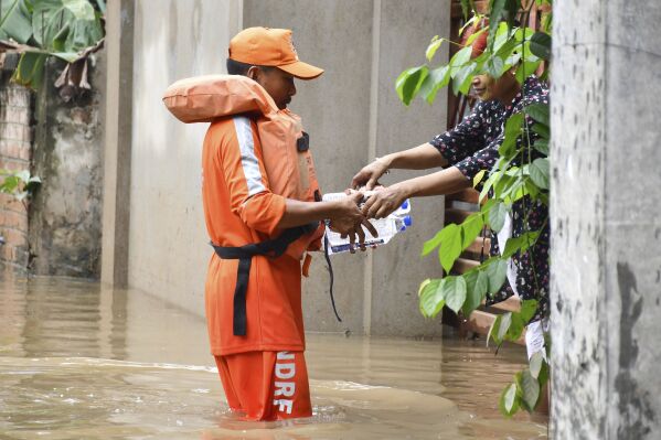 A member of National Disaster Response Force (NDRF) distributes drinking water to a resident after heavy rains flooded the area around her home, in Guwahati, India, Saturday, May 31, 2025. (AP Photo)