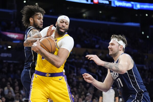 Los Angeles Lakers forward Anthony Davis, center, grabs a rebound between Dallas Mavericks center Dereck Lively II (2) and guard Luka Doncic (77) during the first half of an NBA basketball game Wednesday, Jan. 17, 2024, in Los Angeles. (AP Photo/Marcio Jose Sanchez)