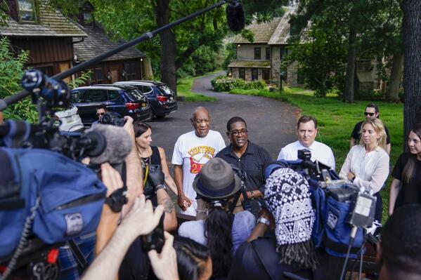 Bill Cosby, center, and spokesperson Andrew Wyatt, right, approach members of the media gathered outside the home of the entertainer in Elkins Park, Pa., Wednesday, June 30,2021. Pennsylvania's highest court has overturned comedian Cosby's sex assault conviction. The court said Wednesday, that they found an agreement with a previous prosecutor prevented him from being charged in the case. The 83-year-old Cosby had served more than two years at the state prison near Philadelphia and was released. (AP Photo/Matt Slocum)