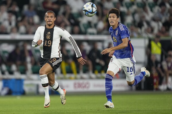 FILE - Germany's Leroy Sane, left, vie for the ball with Japan's Takehiro Tomiyasu during an international friendly soccer match between Germany and Japan in Wolfsburg, Germany, on Sept. 9, 2023. Bakers, singers, entertainers, art venues, radio stations. Germany coach Julian Nagelsmann was supposed to announce his European Championship squad on Thursday, but others have been doing it for him instead. The German soccer federation’s decision to “leak” some of Nagelsmann’s choices in a variety of manners has arguably generated more excitement than the confirmed choices themselves. (Ǻ Photo/Martin Meissner, File)