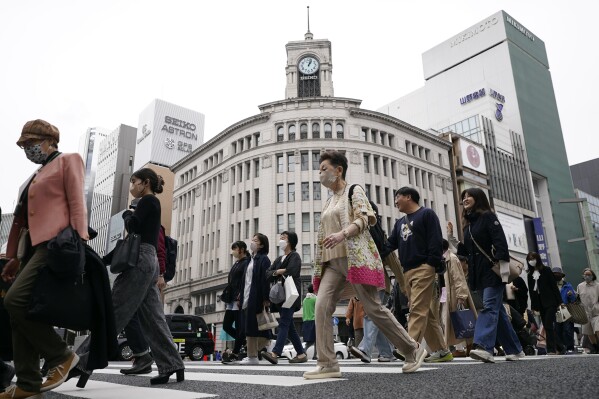 FILE - People walk across a pedestrian crossing in Ginza shopping district in Tokyo on March 31, 2023. Japan’s economy slipped into a contraction in the third quarter, decreasing at an annual pace of 2.1% as consumption and investments shrank, the government reported Wednesday, Nov. 15, 2023. (AP Photo/Eugene Hoshiko, File)