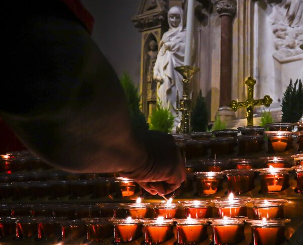 In this Wednesday, Nov. 27, 2019, photo, a Catholic faithful lights candles at a prayer station during a visit to one of the great symbols of the Roman Catholic Church, St. Patrick's Cathedral, in New York. Catholic dioceses are facing a new wave of sexual abuse lawsuits after multiple states extended or suspended the statute of limitations to allow claims stretching back decades. In 2016, New York Archbishop Timothy Dolan established a fund to compensate victims. (AP Photo/Bebeto Matthews)