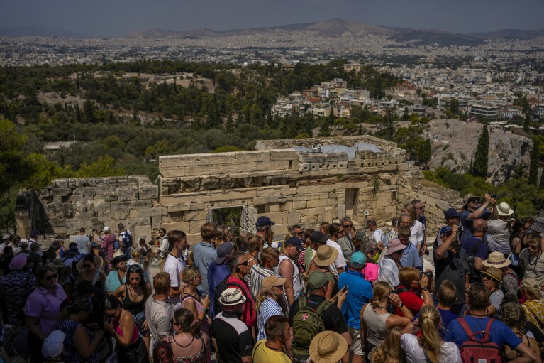 Tourists visit the ancient hill of the Acropolis in Athens, Greece, Tuesday, July 4, 2023. Tourist arrivals in some of Europe's most popular destinations have surpassed 2019 records, with tourists flocking to the Colosseum, Louvre, Acropolis and other major tourist attractions. While European tourists helped the industry recover last year, this summer's economic boom has been largely led by Americans, supported by a strong dollar and, in some cases, pandemic savings.  (AP Photo/Thanasis Stavrakis)