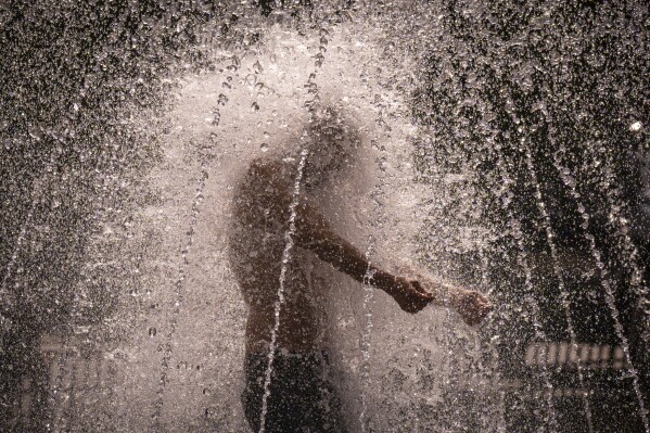 FILE - A man stands in a fountain in Bucharest, Romania, on a hot afternoon, July 25, 2023. July has been so hot so far that scientists calculate that this month will be the hottest globally on record and likely the warmest human civilization has seen, even though there are several days left to sweat. (AP Photo/Andreea Alexandru, File)