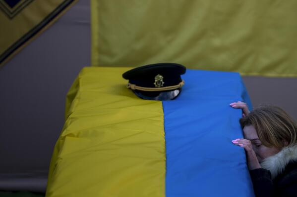 Svitlana kneels next to the coffin of her husband Serhii, 48, during his funeral in Tarasivka village, near Kyiv, Ukraine, Wednesday, Feb. 15, 2023. Serhii Havryliuk, an officer of the Azov Assault Brigade, died while defending the Azovstal steel plant in Mariupol on April 12, 2022 against the Russians. Serhii has finally been buried after DNA tests confirmed his identity. (AP Photo/Emilio Morenatti)