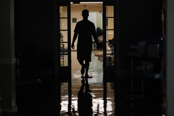 A resident's relative walks through the Peach Tree Village nursing home to collect family possessions from the flooded facility in Brandon, Miss., following a morning of torrential rains, Wednesday, Aug. 24, 2022. Heavy rains and flash flooding prompted rescue operations, closures and evacuations in the central part of the state. (AP Photo/Rogelio V. Solis)