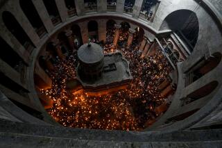 FILE - Christian pilgrims hold candles as they gather during the ceremony of the Holy Fire at Church of the Holy Sepulchre, where many Christians believe Jesus was crucified, buried and rose from the dead, in the Old City of Jerusalem dead, Saturday, April 23, 2022. The Greek Orthodox Church on Wednesday, April 12, 2023, accused Israeli police of infringing on the freedom of worshippers with "heavy-handed” restrictions on how many pilgrims can attend the “Holy Fire” ceremony amid soaring tensions. (AP Photo/Tsafrir Abayov, File)