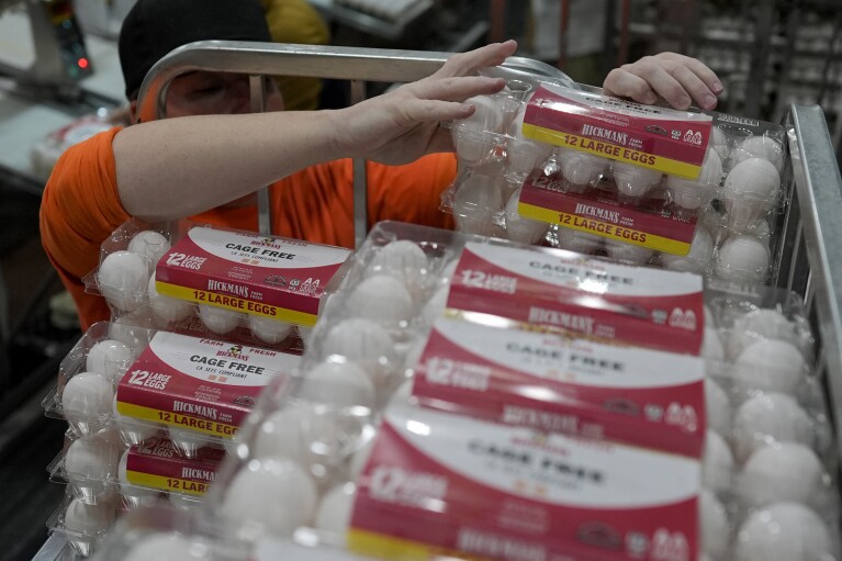 A prison worker, wearing orange, stacks cartons of eggs onto a cart at Hickman's Family Farm egg-packaging operation in Tonopah, Ariz., Thursday, March 14, 2024. (AP Photo/Carolyn Kaster)