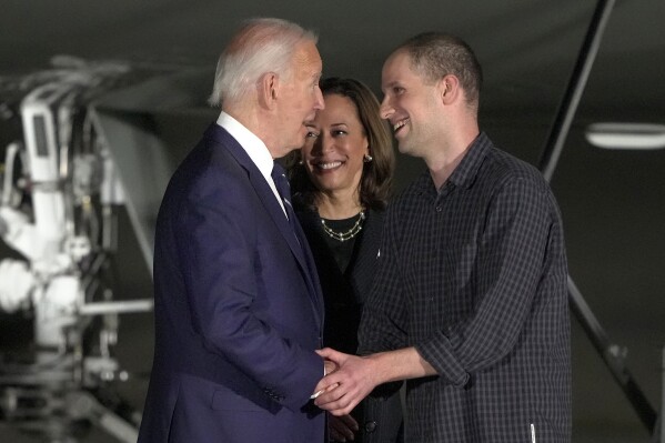 FILE - President Joe Biden, from left, and Vice President Kamala Harris greet reporter Evan Gershkovich at Andrews Air Force Base, Md., following his release as part of a 24-person prisoner swap between Russia and the United States, Aug. 1, 2024. Bloomberg News is apologizing for a premature story written about the prisoner exchange and says it has disciplined the journalists involved. The story was put out by Bloomberg hours before an embargo was lifted by the White House. (AP Photo/Manuel Balce Ceneta, File)
