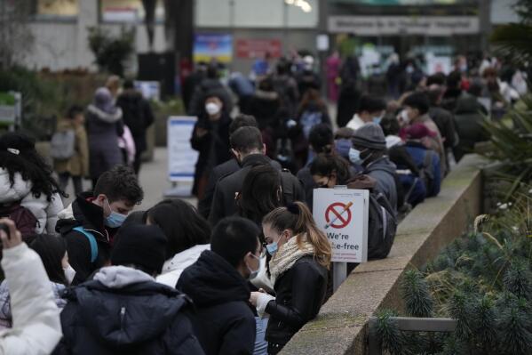 People queue up to go for coronavirus booster jabs at St Thomas' Hospital, in London, Tuesday, Dec. 14, 2021. Long lines have formed for booster shots across England as the U.K. government urged all adults to protect themselves against the omicron variant.  (AP Photo/Matt Dunham)