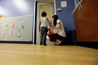 FILE - In this Monday, Oct. 24, 2016 file photo, Megan Krail helps a 4-year-old boy with Autism Spectrum Disorder practice trick-or-treating at The University of Texas at Dallas' Callier Center for Communication Disorders preschool class in Dallas. According to a report by the Centers for Disease Control and Prevention released on Thursday, April 26, 2018, the estimate of how common autism is again going up slightly, after seeming to level off for a couple of years. (AP Photo/LM Otero)