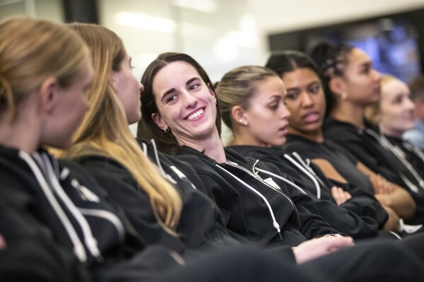 Iowa's Caitlin Clark, center, awaits her NCAA college basketball team's seed reveal during a 