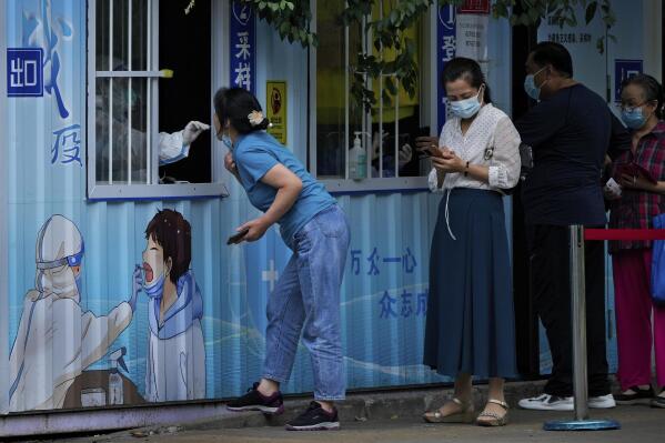Residents get their routine COVID-19 throat swabs at a coronavirus testing site along a street in Beijing, Monday, Aug. 29, 2022. (AP Photo/Andy Wong)