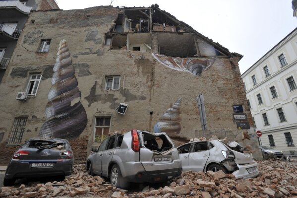 A collapsed wall leaves an exposed home and crushed cars after an earthquake in Zagreb, Croatia, Sunday, March 22, 2020. A strong earthquake shook Croatia and its capital on Sunday, causing widespread damage and panic. (AP Photo)