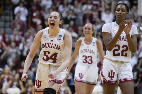 Indiana forward Mackenzie Holmes (54) celebrates with teammate Sydney Parrish (33) and Chloe Moore-McNeil (22) in the second half of a second-round college basketball game against Oklahoma in the NCAA Tournament, Monday, March 25, 2024, in Bloomington, Ind. Indiana defeated Oklahoma 75-68. (AP Photo/Michael Conroy)