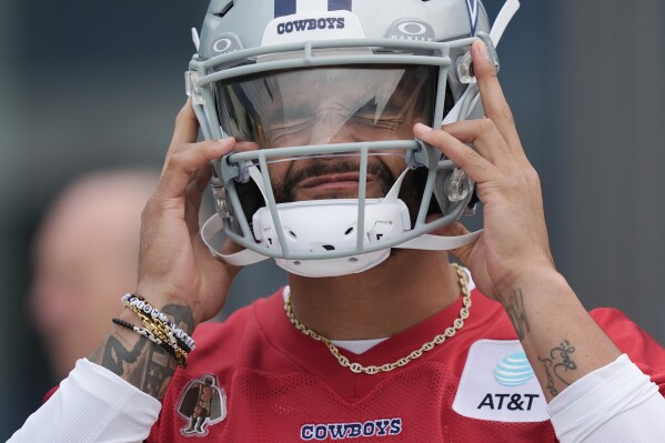Dallas Cowboys quarterback Dak Prescott puts on his helmet before an NFL football team practice in Frisco, Texas, Wednesday, May 22, 2024. (AP Photo/LM Otero)