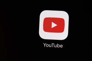 FILE - This March 20, 2018 file photo shows the YouTube app on an iPad in Baltimore. YouTube is following the lead of Twitter and Facebook, saying that it is taking more steps to limit QAnon and other baseless conspiracy theories that can lead to real-world violence. The Google-owned video platform said Thursday, Oct. 15, 2020  it will now prohibit material targeting a person or group with conspiracy theories that have been used to justify violence. (AP Photo/Patrick Semansky, File)
