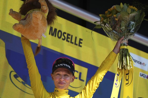 Katarzyna Niewiadoma of Poland, wearing the overall leader's yellow jersey, celebrates on the podium after the fifth stage of the Tour de France Women cycling race with start in Bastogne, Belgium and finish in Amneville, France, Thursday, Aug. 15, 2024. (AP Photo/Peter Dejong)