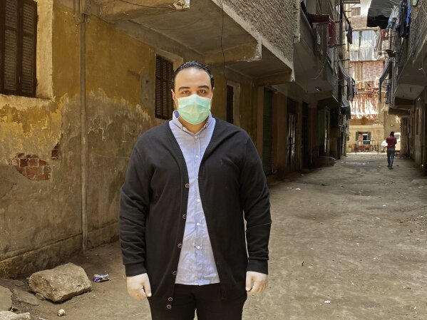 In this April 17, 2020 photo, Dr. Sherif Waheed poses on a street where 73-year-old Ghaliya Abdel-Wahab died from COVID-19 on April 6, 2020, on one of two streets on complete lockdown closed off by security forces for people to quarantine after her death, in Bahtim, Shubra el-Kheima neighborhood, Qalyoubiya governorate, Egypt. (AP Photo/Nariman El-Mofty)