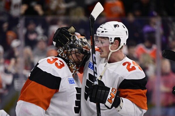 Philadelphia Flyers goaltender Samuel Ersson, left, and Nick Seeler celebrate after their a victory in an NHL hockey game against the New Jersey Devils, Saturday, April 13, 2024, in Philadelphia. (AP Photo/Derik Hamilton)