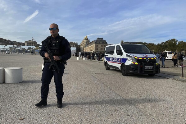 Security stands near the grounds of The Palace of Versailles on Tuesday, Oct. 17, 2023 in Versailles, France. One of France's most visited tourist attractions, was evacuated for a security scare, for the the second time in four days, with France on heightened alert against feared attacks after the fatal stabbing of a school teacher. (AP Photo/Pat Eaton-Robb)