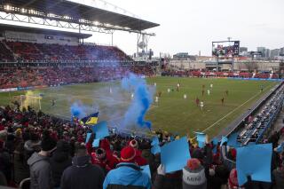 Toronto FC's fans set off blue-and-yellow flares and hold up colored cards to show their support for Ukraine during the first half of an MLS soccer match against the New York Red Bulls, in Toronto, Saturday, March 5, 2022. (Chris Young/The Canadian Press via AP)