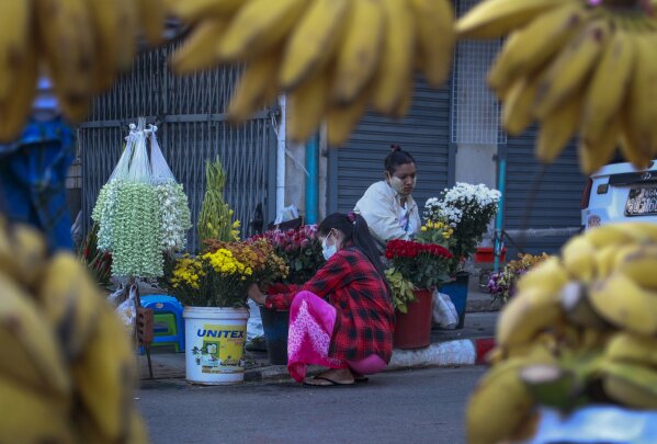 Woman arrange flowers in a street market Yangon, Myanmar, Tuesday, Feb. 2, 2021. Hundreds of members of Myanmar's Parliament remained confined inside their government housing in the country's capital on Tuesday, a day after the military staged a coup and detained senior politicians including Nobel laureate and de facto leader Aung San Suu Kyi. (AP Photo/Thein Zaw)