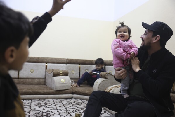 Khalil Al-Sawadi holds a one-year-old Afraa al-Sudani at his home in Jinderis, Syria, Sunday, Feb. 4, 2024. Afraa was pulled alive from the rubble of her family's house in the town of Jinderis in northern Syria, still attached by an umbilical cord to her dead mother on February 6, 2023, after a devastating earthquake hit Turkey and Syria. Afraa is the only surviving member of her immediate family. (AP Photo/Ghaith Alsayed)