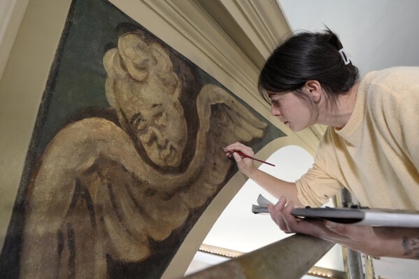 Conservator Corrine Long, of Dover, N.H., restores nearly 300-year-old painted angels on walls of Old North Church, Wednesday, Dec. 18, 2024, in Boston. (AP Photo/Steven Senne)
