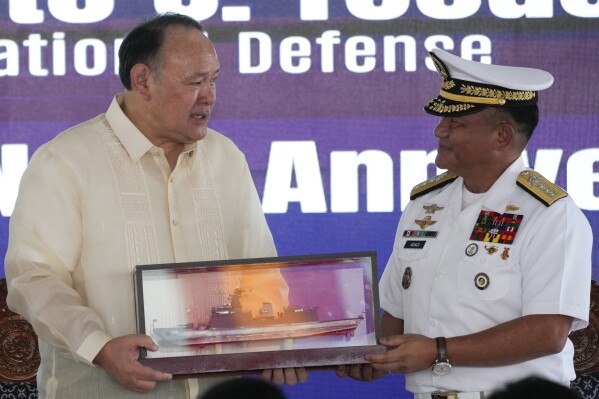 Philippine Defense Secretary Gilberto Teodoro, left, receives a memento from Philippine Navy Chief, Vice Adm. Toribio Adaci Jr, during the 126th Philippine Navy anniversary in Manila, Philippines on Friday, May 24, 2024. The Philippines would press efforts to build security alliances and stage realistic combat drills, including joint naval sails with the United States, Japan and Australia in disputed waters, to defend its territorial interests, Defense Secretary Gilberto Teodoro said Friday, dismissing China's criticisms of such moves as a sign of paranoia. (AP Photo/Aaron Favila)
