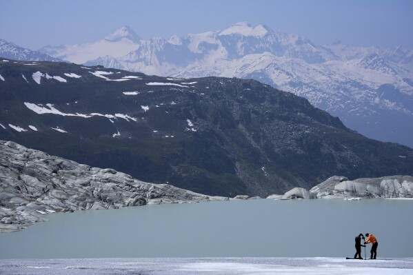 Matthias Huss, of the Federal Institute of Technology in Zurich and glacier monitoring group GLAMOS, and Monica Ursina Jaeger prepare a camera at the Rhone Glacier near Goms, Switzerland, June 10, 2025. (AP Photo/Matthias Schrader)