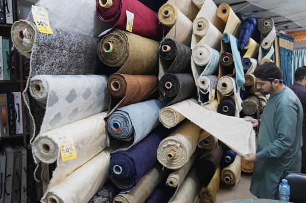 A vendor displays linen sofa fabric in a house linens store at a market in Lahore, Pakistan, Thursday, April 3, 2025. (AP Photo/K.M. Chaudary)