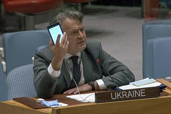 In this image from UNTV video, Ukraine's Ambassador to the United Nations Sergiy Kyslytsya, holds up a phone as he speaks an emergency meeting of the U.N. Security Council Wednesday, Feb. 23, 2022, at U.N. headquarters. (UNTV via AP)