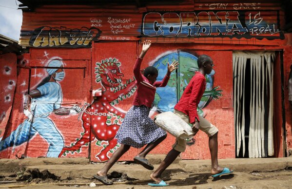 FILE - In this June 3, 2020, file photo, children run past al mural warning people about the dangers of the coronavirus, in the Kibera settlement in Nairobi, Kenya. The pandemic has fractured global relationships as governments act in the interest of their citizens first, but John Nkengasong, Africa's top public health official, has helped to steer the continent's 54 countries into an alliance praised as responding better than some richer nations. (AP Photo/Brian Inganga, File)