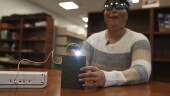 Minh Ha, assistive technology manager at the Perkins School for the Blind tries a LightSound device for the first time at the school's library in Watertown, Mass., on March 2, 2024. As eclipse watchers look to the skies in April 2024, new technology will allow people who are blind or visually impaired to hear and feel the celestial event. (AP Photo/Mary Conlon)
