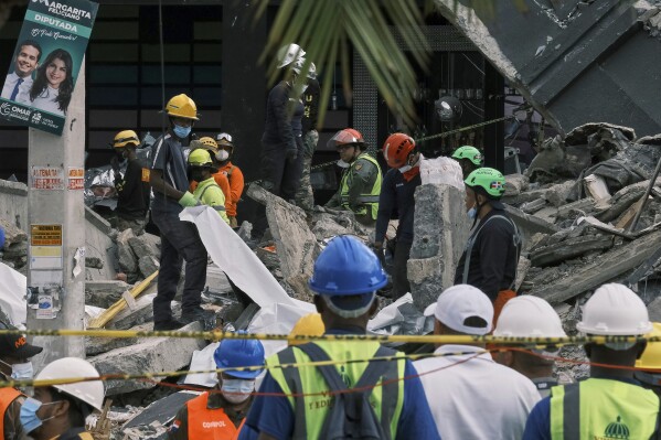 Rescue workers use sheets as they recover bodies from the rubble at the Jet Set nightclub after its roof collapsed two nights prior during a merengue concert in Santo Domingo, Dominican Republic, Wednesday, April 9, 2025. (AP Photo/Ricardo Hernandez)