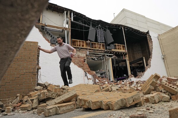 A man walks over fallen bricks from a damaged building in the aftermath of a severe thunderstorm Friday, May 17, 2024, in Houston. Thunderstorms pummeled southeastern Texas on Thursday, killing at least four people, blowing out windows in high-rise buildings and knocking out power to more than 900,000 homes and businesses in the Houston area. (AP Photo/David J. Phillip)