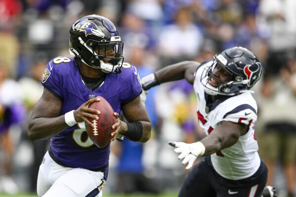 Baltimore Ravens' Lamar Jackson rolls past Houston Texans' Will Anderson Jr. during the second half of an NFL football game Sunday, Sept. 10, 2023, in Baltimore. (AP Photo/Nick Wass)