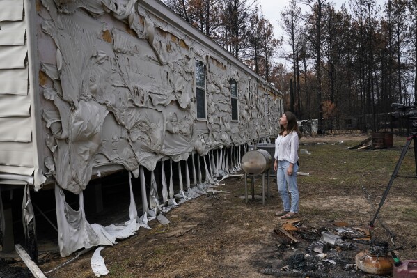 Lindsay Bustamante looks at the damage to her home in the aftermath of a wildfire in Evans, La., Wednesday, Sept. 13, 2023. (AP Photo/Gerald Herbert)