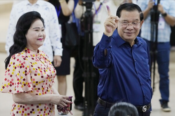 Cambodian Prime Minister Hun Sen, right, of the Cambodian People's Party (CPP) shows off his inked finger, standing next to his wife Bun Rany, left, after voting a ballot at a polling station in Takhmua in Kandal province, southeast Phnom Penh, Cambodia, Sunday, July 23, 2023. Cambodians go to the polls Sunday with incumbent Prime Minister Hun Sen and his party all but assured a landslide victory thanks to the effective suppression and intimidation of any real opposition that critics say has made a farce of democracy in the Southeast Asian nation. (AP Photo/Heng Sinith)