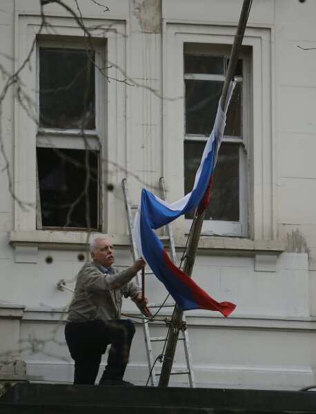 
              A man works to untangle the national flag flown from the Russian Embassy, after it became entangled on its staff at the embassy in London, Wednesday, March 14, 2018. Britain announced Wednesday it will expel 23 Russian diplomats, the biggest such expulsion since the Cold War, and break off high-level contacts with the Kremlin over the nerve-agent attack on a former spy and his daughter in an English town.(AP Photo/Alastair Grant)
            