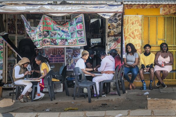 Customers have their nails done near the Baragwanath taxi rank in Soweto, South Africa, Wednesday Sept. 16, 2020. South African president Cyril Ramaphosa is scheduled to address the nation later in the day, as case numbers and death from Covid-19 hit the lowest in months. (AP Photo/Jerome Delay)