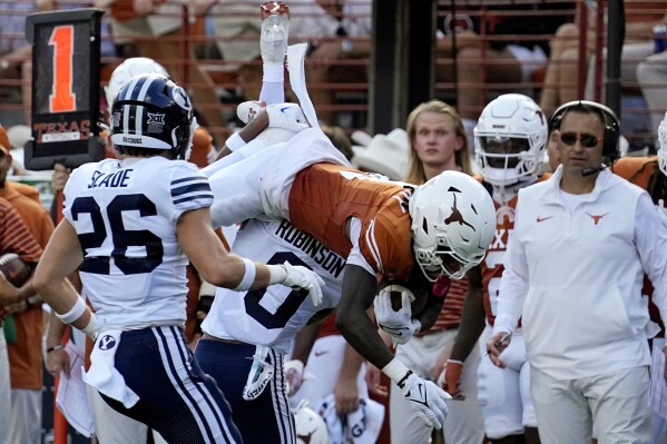 Texas wide receiver Xavier Worthy (1) is upended by BYU cornerback Jakob Robinson (0) during the first half of an NCAA college football game in Austin, Texas, Saturday, Oct. 28, 2023. (AP Photo/Eric Gay)