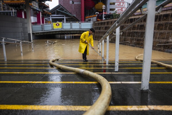 A worker clears water on a flooded street following heavy rainstorms in Hong Kong, Friday, Sept. 8, 2023. Rain pouring onto Hong Kong and southern China overnight flooded city streets and some subway stations, halting transportation and forcing schools to close Friday. (AP Photo/Louise Delmotte)