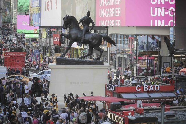 A bronze sculpture, "Rumors of War," by artist Kehinde Wiley, appears in Times Square at an unveiling on Friday Sept. 27, 2019, in New York. The work, depicting of a young African American in urban streetwear sitting astride a galloping horse, will be exhibited through December 1.  (AP Photo/Bebeto Matthews)