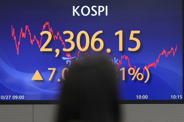 A currency trader walks by the screens showing the Korea Composite Stock Price Index (KOSPI) at a foreign exchange dealing room in Seoul, South Korea, Friday, Oct. 27, 2023. Asian shares advanced Friday after the latest tumble on Wall Street, where the S&P 500 fell to its lowest level in five months. (AP Photo/Lee Jin-man)