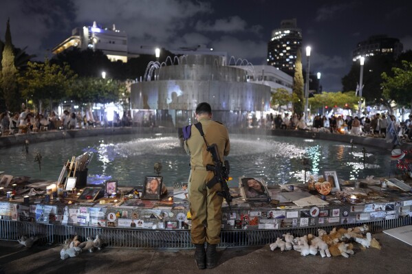 An Israeli soldier pays respect at a memorial for victims of the bloody Oct. 7, cross-border attack by Hamas militants on the eve of Israel's annual Memorial Day for fallen soldiers and victims of nationalistic attacks, in Tel Aviv, Israel, Sunday, May 12, 2024. (AP Photo/Oded Balilty)