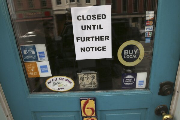 FILE - In this March 25, 2020 file photo, a closed sign hangs in the window of a shop in Portsmouth, N.H., due to caronavirus concerns. Hundreds of cities and counties grappling with the economic fallout caused by the pandemic might receive little, if any, of the emergency funding allotted for state and local governments in the $2.2 trillion coronavirus stimulus package.  (AP Photo/Charles Krupa, File)