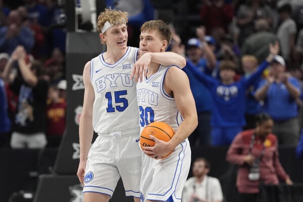 Brigham Young's Richie Saunders (15) and Dallin Hall (30) celebrate after defeating Iowa State during an NCAA college basketball game in the quarterfinal round of the Big 12 Conference tournament, Thursday, March 13, 2025, in Kansas City, Mo. (AP Photo/Charlie Riedel)