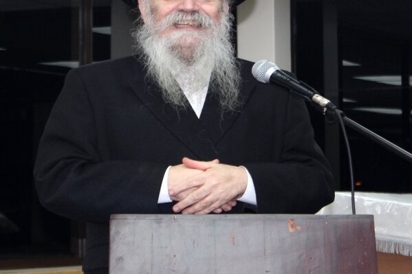 In this Dec. 20, 2017 photo provided by Joel Friedman, Rabbi Avrohom Pinter makes a speech at Canvey Island,in Essex, southeast England. Pinter gave his life to save his neighbors. When the British government ordered a lockdown to slow the spread of coronavirus, Pinter went door-to-door to deliver the public health warning to the ultra-Orthodox Jews in northeast London. Within days, the 71-year-old rabbi had caught the disease and died.  (Joel Friedman via AP)